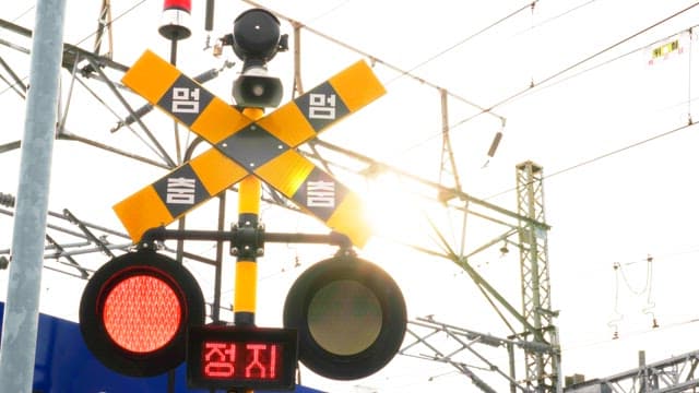 Red traffic light indicating a stop sign at a railroad crossing with trains running