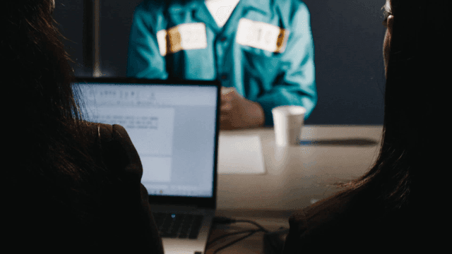 Prisoner and investigator with laptop and documents