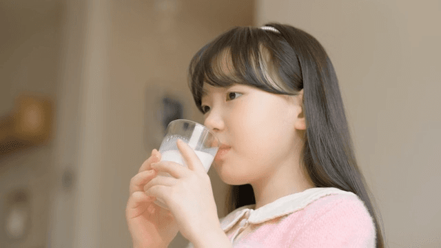 Young girl drinking milk indoors