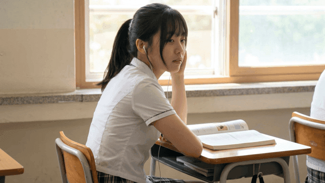 Students listening to music with earphones in classroom