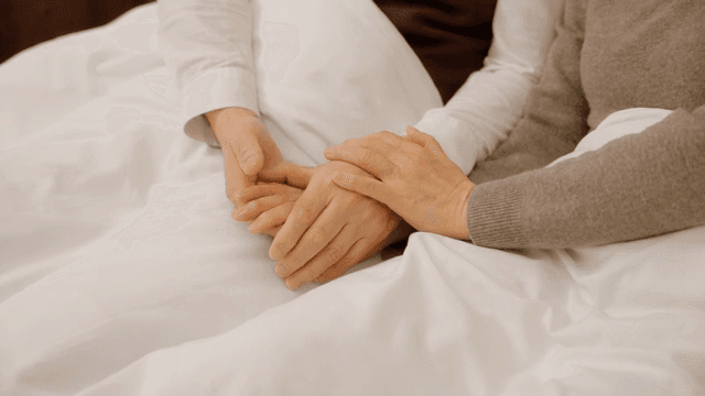 침대에서 손을 잡고 있는 두 사람