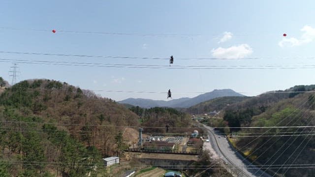산악 지역의 송전탑을 점검하기 위해 전깃줄에 매달린 작업자들