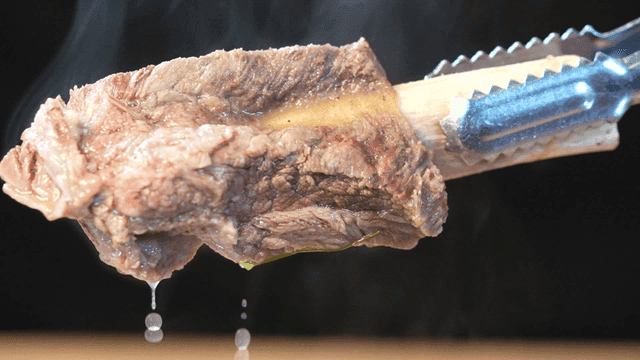 Steaming beef rib held with tongs