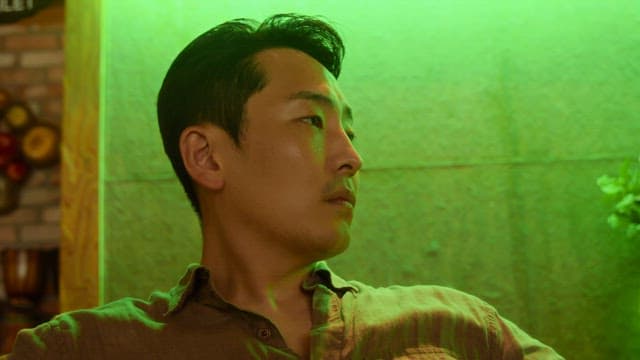 초록색 조명 실내에서 주변을 둘러보는 남자