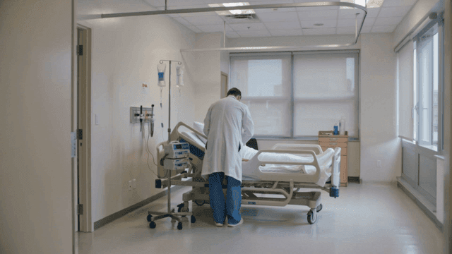 Back view of doctor caring for patient in hospital room