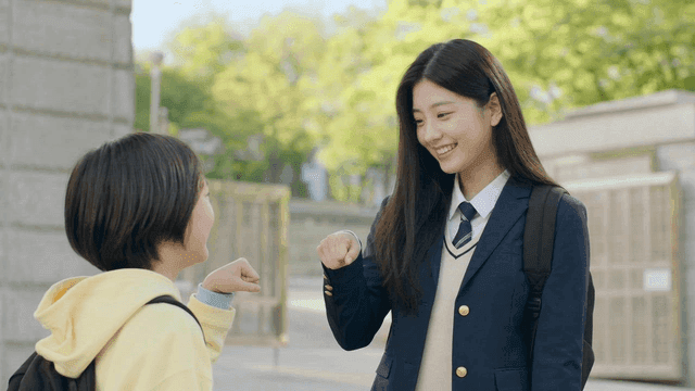 Child exchanging fist bump with student in school uniform