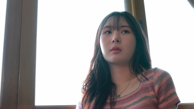 창가에 앉아 생각에 잠긴 여성