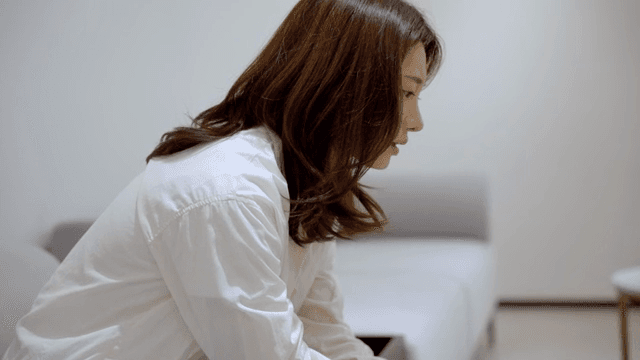 소파에 앉아 초조하게 무언가를 기다리는 여성