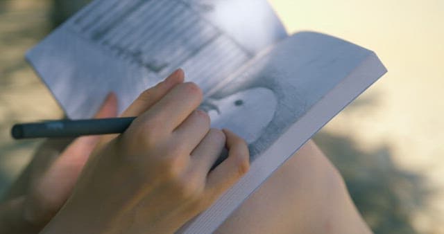 Person Drawing in a Sketchbook Outdoors