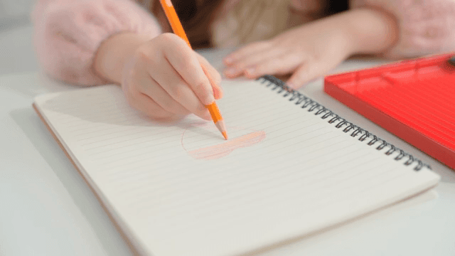 색연필로 노트에 그림을 그리는 아이