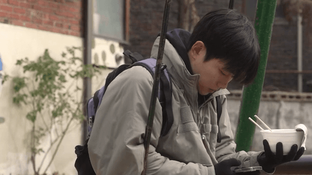 놀이터에서 라면을 먹다가 핸드폰을 확인하는 남성