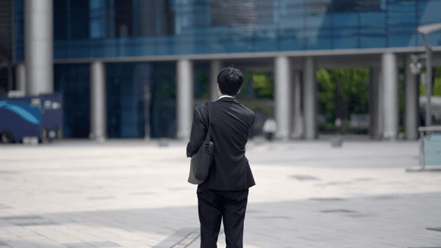 Office worker standing on the street and looking at company building