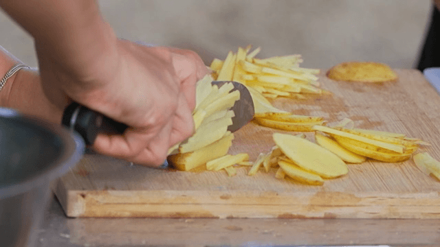 Slicing potatoes on a wooden cutting board
