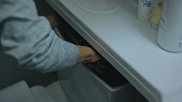 Person Taking Out an Object Hidden in a Toilet Tank