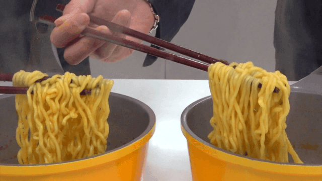 Lifting ramen from pot with long wooden chopsticks