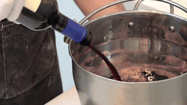 Red wine bottle poured into large pot