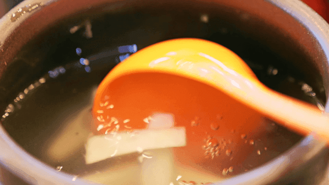 Ladle stirring radish kimchi in jar
