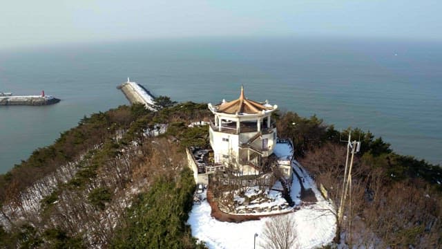 Snow-coveredobservatory on a hill overlooking the sea