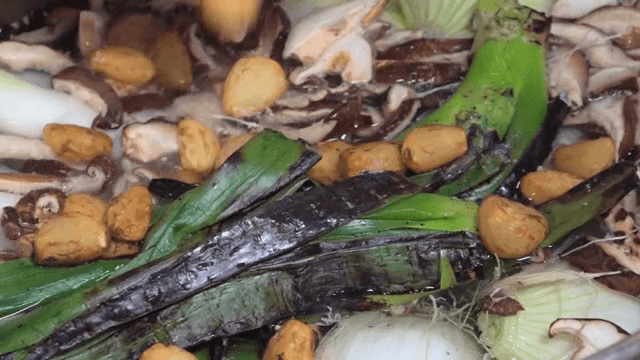 다양한 재료가 있는 냄비에 구운 마늘을 추가하는 장면