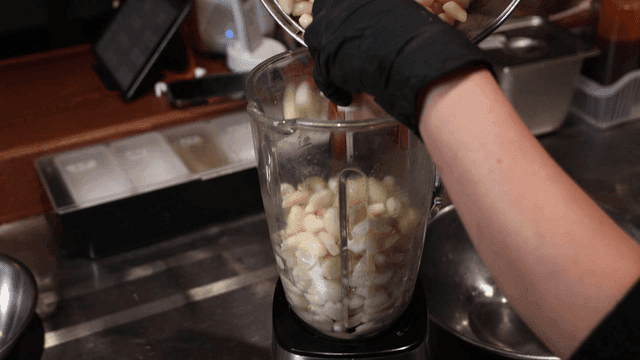 Hand pouring garlic into blender
