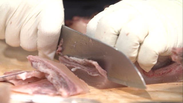 Cutting cooked beef with gloved hands