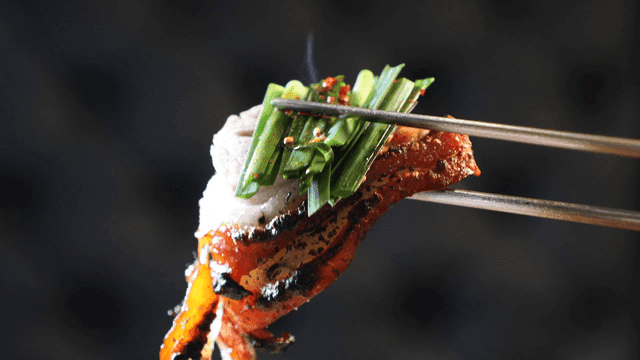 Chopsticks holding chives and spicy pig's trotters