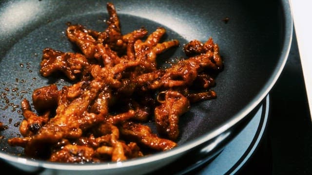 Stir-Fried Chicken Feet Cooking in a Frying Pan