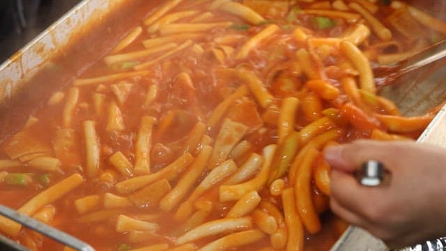 Stirring Spicy Tteokbokki in Boiling Red Sauce