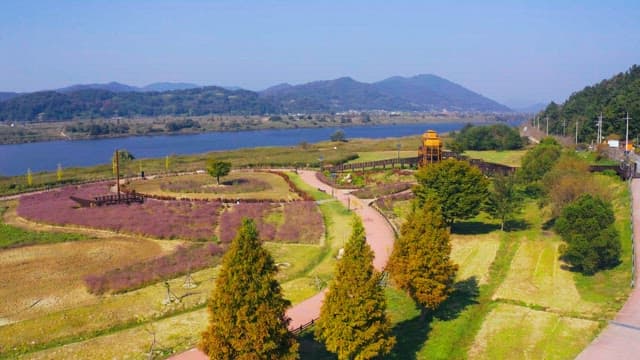 View of a serene park with pathways and scenic river surrounded by nature