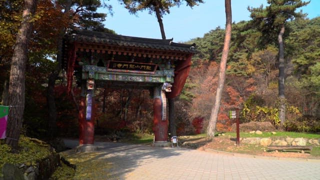 가을 숲 공원에서 전통적인 나무문을 지나가는 관광객들