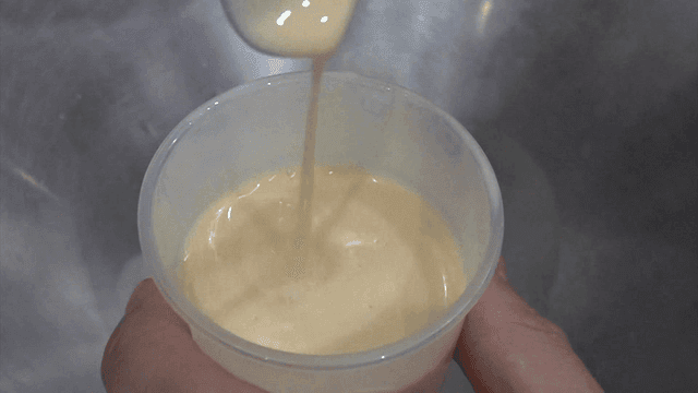 Stirring yellow yogurt poured into a plastic cup