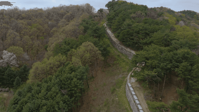 숲으로 둘러싸인 산비탈을 따라 이어진 성벽 길