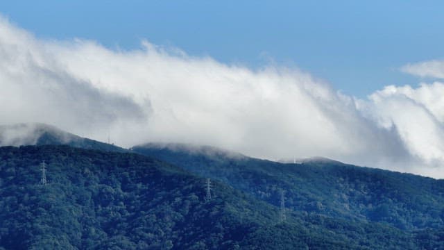 Clouds covering a lush green mountain