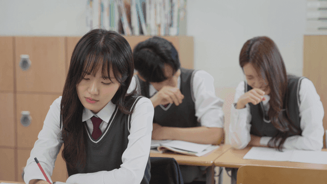 뒷자리에서 서로 웃는 두 학생과 불안한 표정의 앞자리 학생