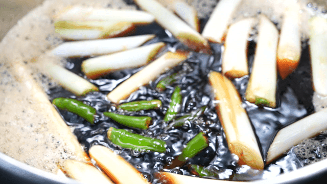 Green chili peppers and green onions in boiling soy sauce