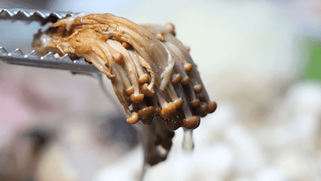Tongs for lifting cooked mushroom stew from pot