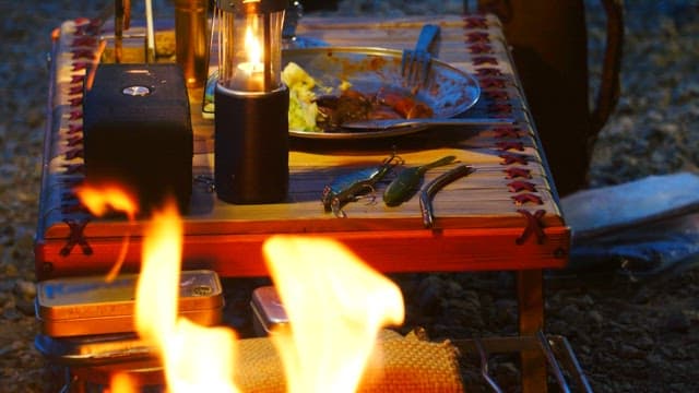 Setting out fishing bait on a camping table next to a campfire