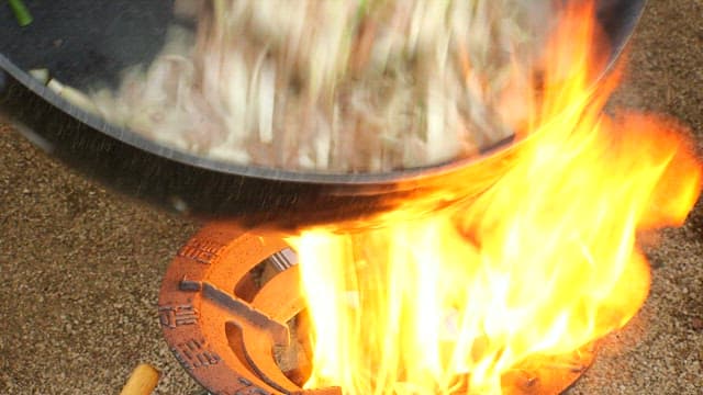 Stir-frying meat and vegetables outdoors