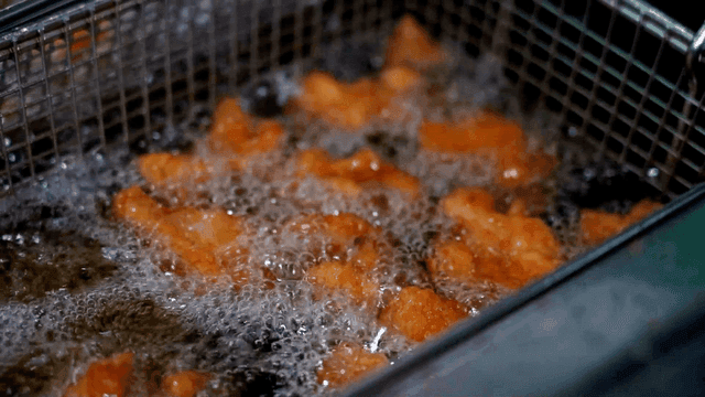 Golden fried chicken sizzling in oil