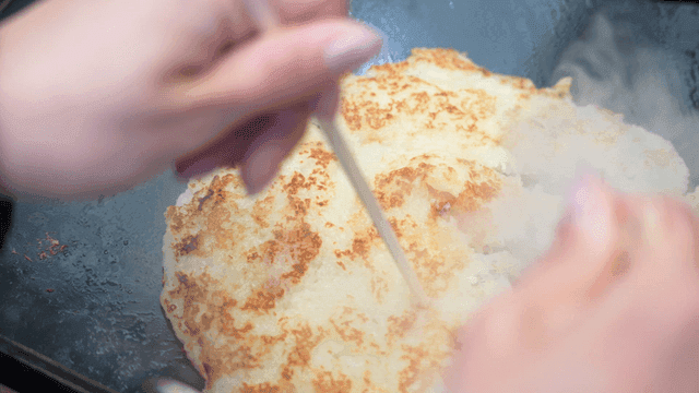 Potato pancakes torn apart with chopsticks on hot iron plate
