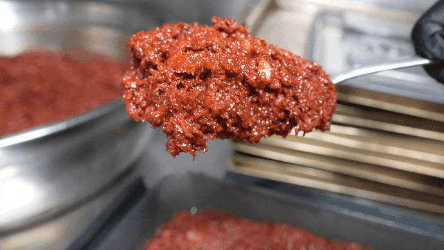 Spoon scooping out chili sauce from container