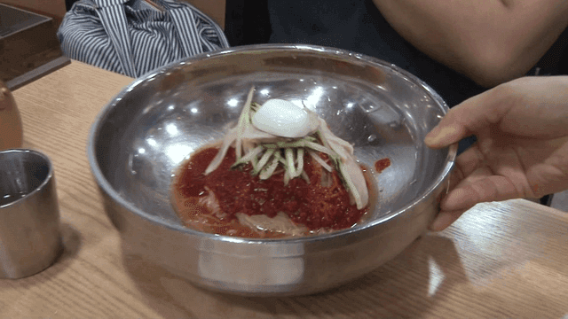 테이블 위에 서빙되는 매운 소스를 곁들인 밀면