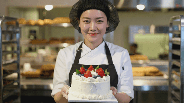 Baker showcasing decorated fresh cream cake