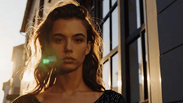 햇빛이 비치는 거리에 서있는 여성