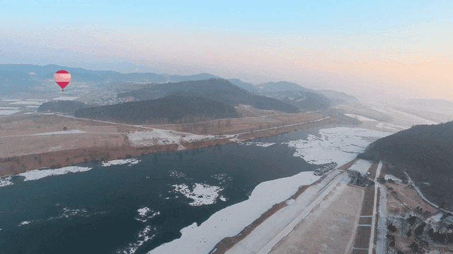 Hot air balloons over snow-covered river
