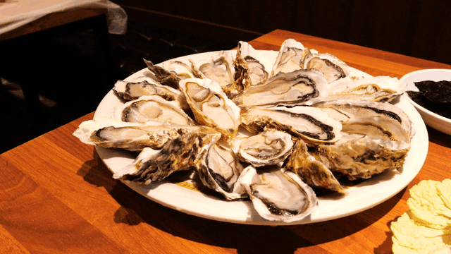 Plate of fresh raw oysters on wooden table
