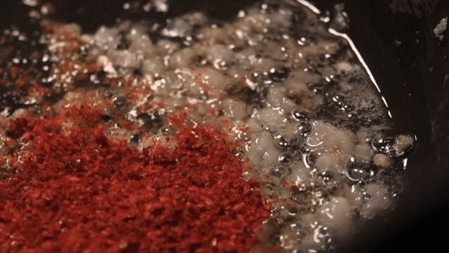Ingredients frying in a pan with red pepper power