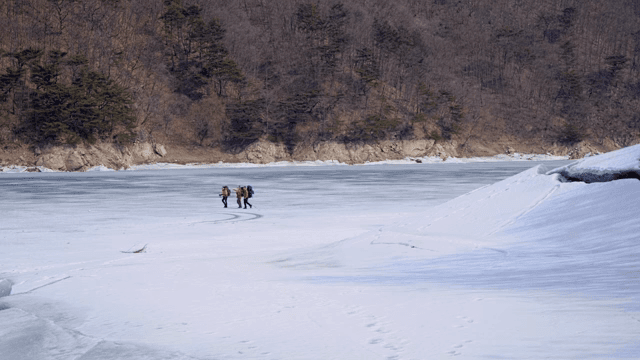 얼어붙은 호수를 걷는 하이커들