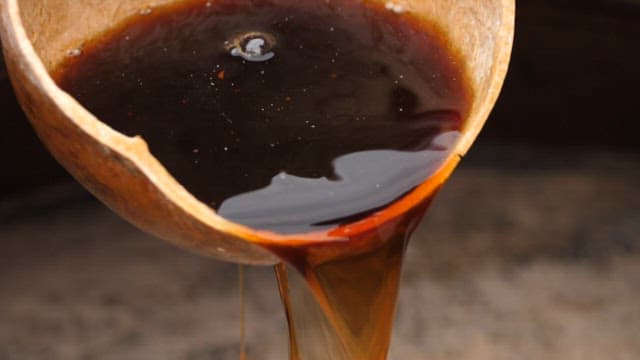 Pouring soy sauce intp a crock jar with a wooden ladle