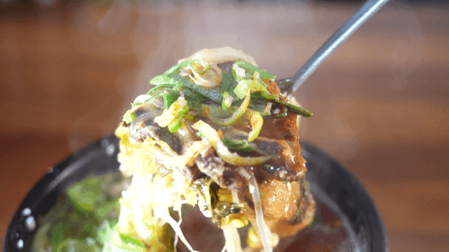Spoon scooping out hot beef hangover soup with vegetables